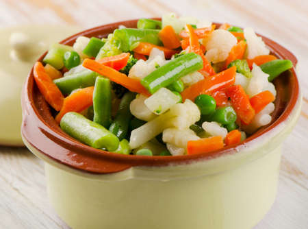 Mixed vegetables in clay  bowl on a wooden tableの写真素材