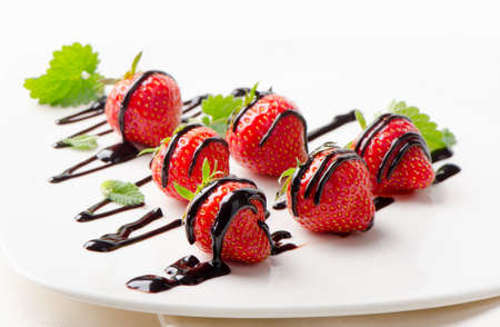 Fresh strawberries  in chocolate sauce on a white plate. Selective focusの写真素材