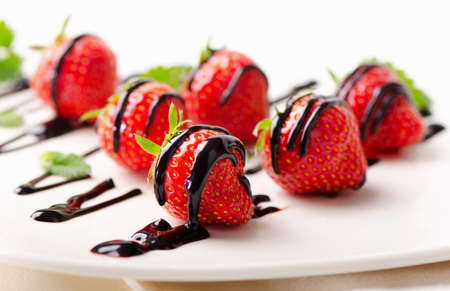 Fresh strawberries  in chocolate sauce on  white plate. Selective focusの写真素材