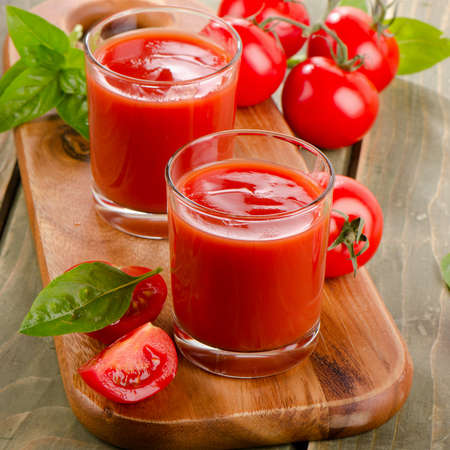 Tomato juice and ripe tomatoes  on  wooden background. Selective focusの写真素材