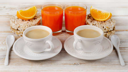 Healthy breakfast with  two coffee cup, orange juice  on a white wood table.の写真素材