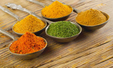 Dried ground spices on spoons on a wooden backgroundの写真素材