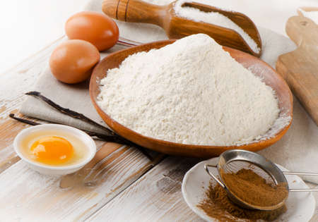 Baking ingredients - eggs, flour, sugar, butter and spices on  a white wooden tableの写真素材