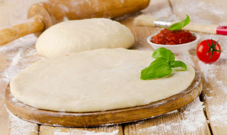 pizza dough with tomato sauce andfresh  basil on  a wooden tableの写真素材