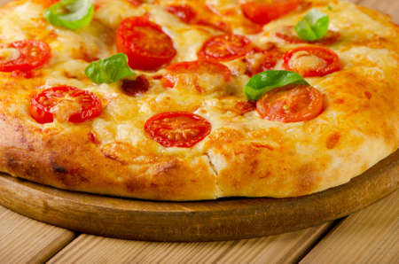 Homemade  pizza with tomatoes on a wooden background.の写真素材