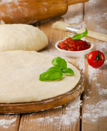 pizza dough with tomato sauce and   basil on  a wooden background .の写真素材