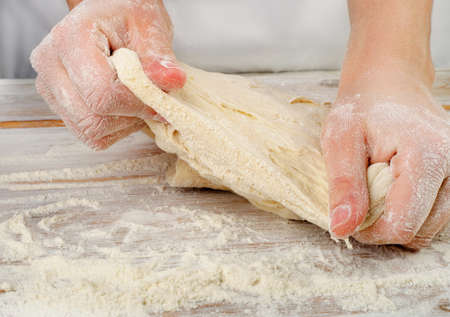 Hands in flour  kneading dough. Selective focus