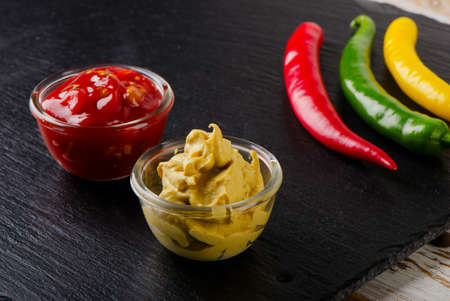 tomato and mustard sauce on a black table. Selective focus
