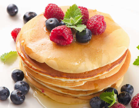 Sweet pancakes with raspberries and blueberies on a  white plate.の写真素材