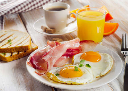 breakfast with fried eggs, bacon,toasts, juice and coffee.Selective focusの写真素材