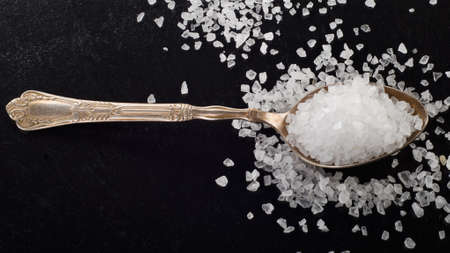 Salt in spoon on  black background. Selective focusの写真素材