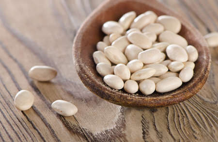White beans in a old wooden spoon. Selective focus