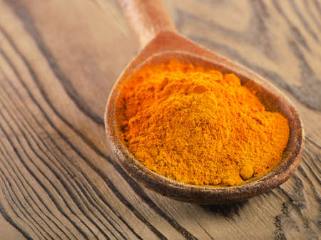 Turmeric powder in a wooden spoon. Selective focusの写真素材