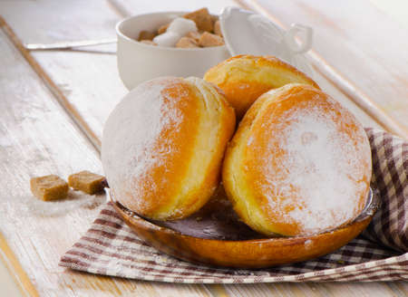 Homemade Donuts with powdered sugar on  wooden plate. Selective focus