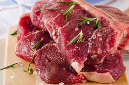 Raw T-Bone Steak with Seasoning  on a wooden board. Selective focus