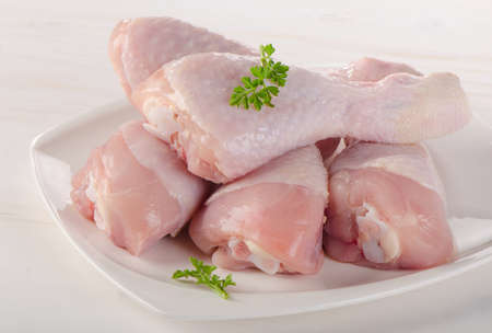 Fresh chicken legs on a white plate.の写真素材