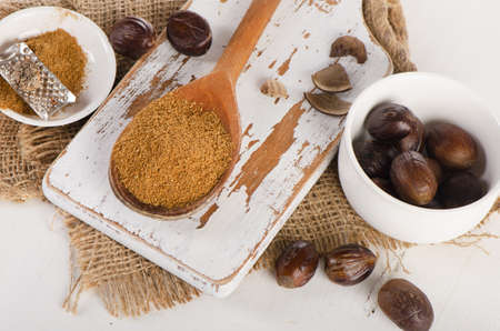 Raw Organic ground  Nutmeg on  white wooden cutting board. Selective focusの写真素材