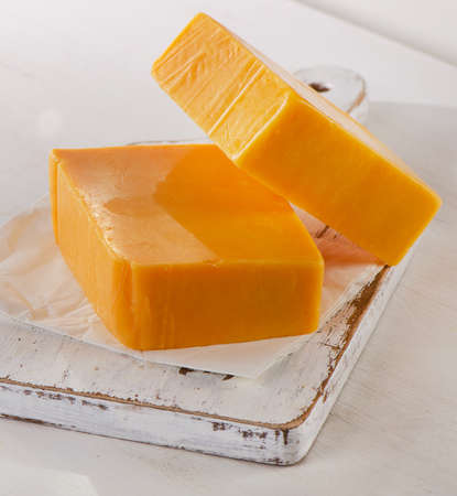Cheddar Cheese on a white wooden Cutting Boardの写真素材
