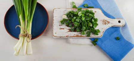 Chopped fresh green onions on  white wooden cutting board. Top viewの写真素材