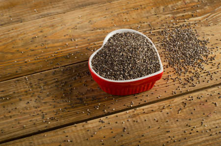 chia seeds in a heart shaped bowl on a rustic wooden table. Selective focusの写真素材