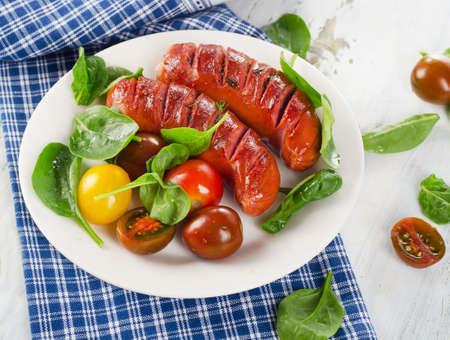 Fried sausages with fresh salad on white plate. Top viewの写真素材