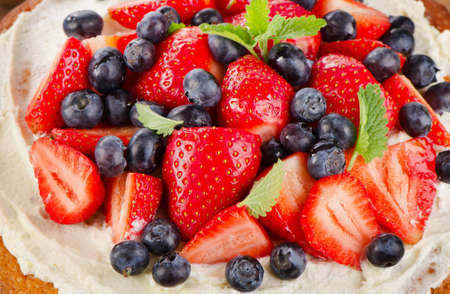 Strawberry and blueberry  cream cake on  wooden background. Top viewの写真素材
