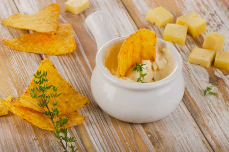 Cheese Sauce with Nachos on a wooden background. Selective focus
