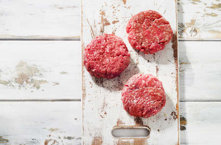 Raw Ground beef meat Burger steak patties on a wooden cutting board. Top viewの写真素材