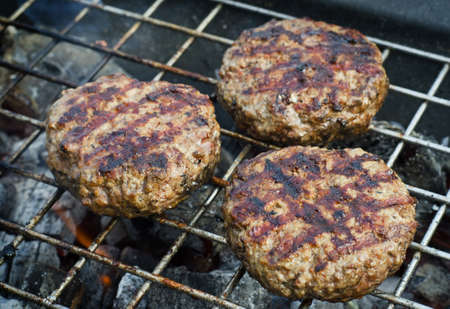 Burgers patties over flames on a grill. Selective focusの写真素材
