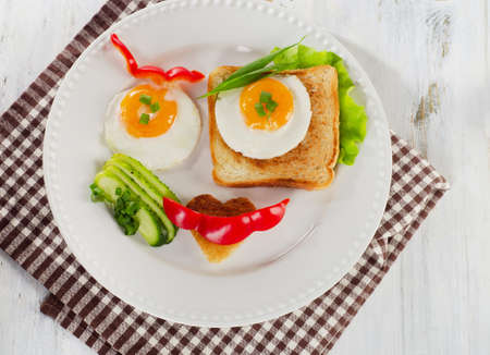 Fried eggs with toast and fresh vegetables for a breakfast
