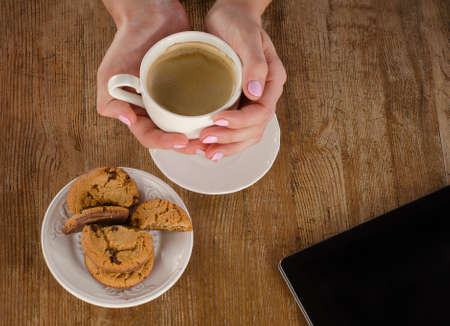 Woman hands with coffee cup and tablet computer. View from aboveの写真素材