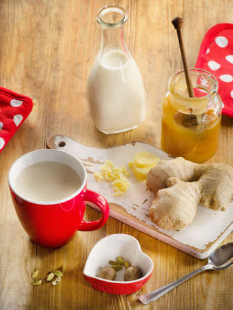 Ginger tea with milk in a red cup on a wooden background. Selective focusの写真素材