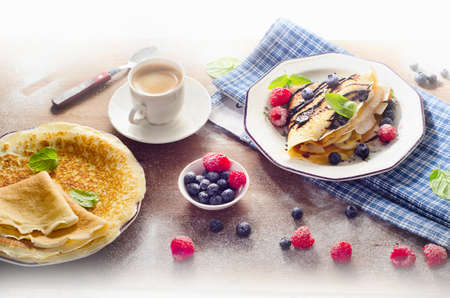 Pancakes with fresh berries, Chocolate cream and cup of coffee for breakfast.の写真素材