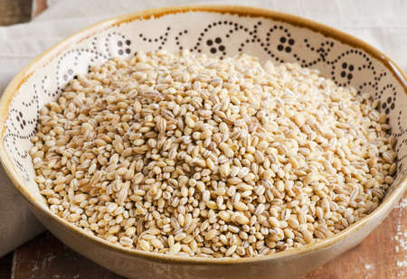 Barley in ceramic bowl on  wooden board. Selective focusの写真素材