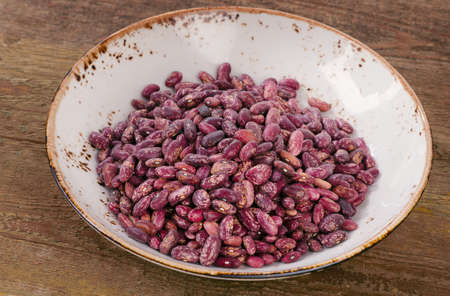 Beans in a bowl on wooden table.