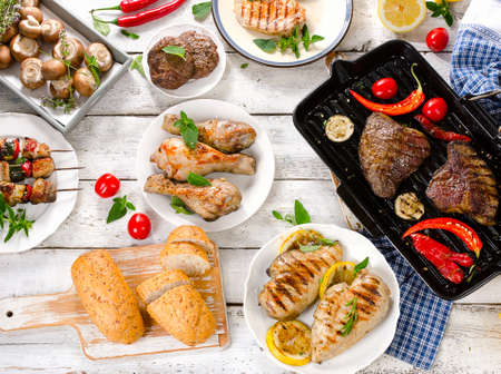 Assorted grilled meat with vegetable on a white wooden table. Top viewの写真素材