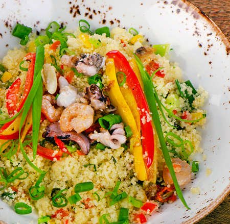 Couscous with vegetables and seafood  on wooden table.  Top viewの写真素材