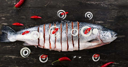 Raw salmon with herbs and spices on a dark rustic board. Top view. Fish preparing for cooking. Healthy food or diet nutrition concept.の写真素材