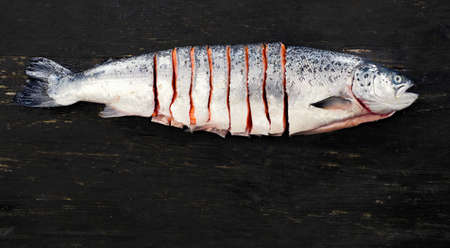 Raw salmon on  dark rustic board. Top view. Fish preparing for cooking. Healthy food or diet...