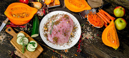 Raw fresh turkey breast, vegetables and seasonings on dark wooden table. Top viewの写真素材