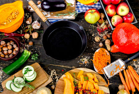 Iron pan with Autumn fruits and vegetables  on dark wooden background. Top viewの写真素材