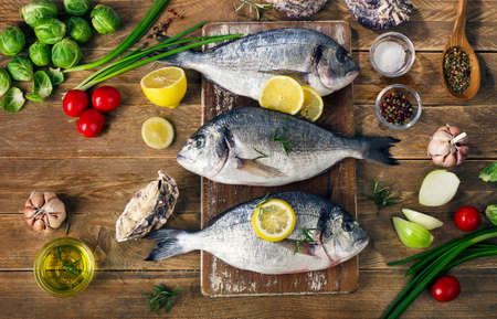 Fresh  raw fish with herbs, spices and vegetables on  a wooden background. Healthy eating concept. Top viewの写真素材