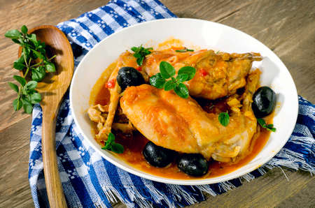 Stewed rabbit legs with black olives and herbs leaves.の写真素材