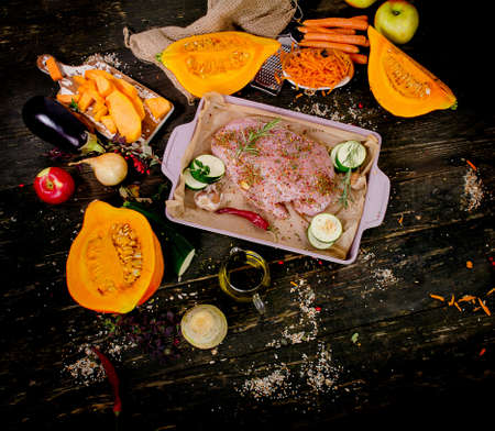 Raw turkey breast and vegetables  on  dark wooden board. Top viewの写真素材