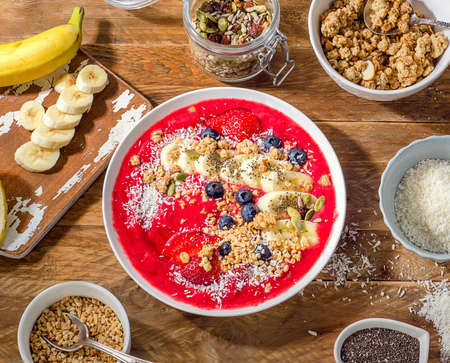 Breakfast berry smoothie bowl topped with banana, strawberry, blueberry, pumpkin and chia seeds. Healthy diet eating. Top view