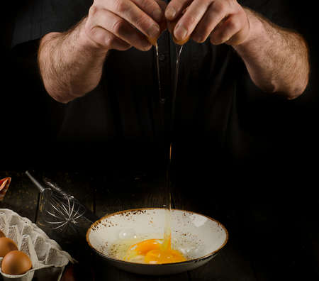 Mature Man hands cracking egg on black backgroundの写真素材