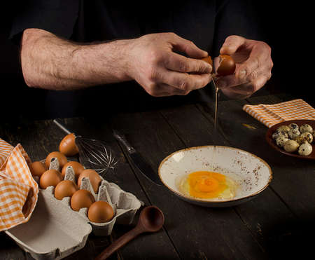 Man hands cracking an egg. Dark backgroundの写真素材