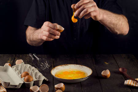 Mature Man hands cracking eggs on a black backgroundの写真素材