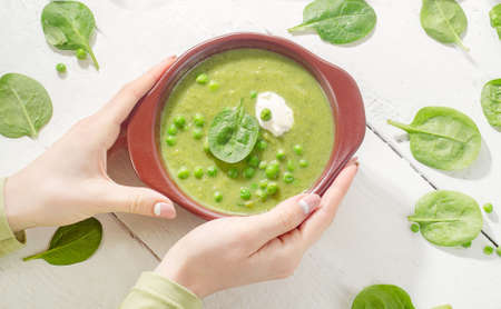 Woman hands holding  Bowl of green pea soup. Top viewの写真素材