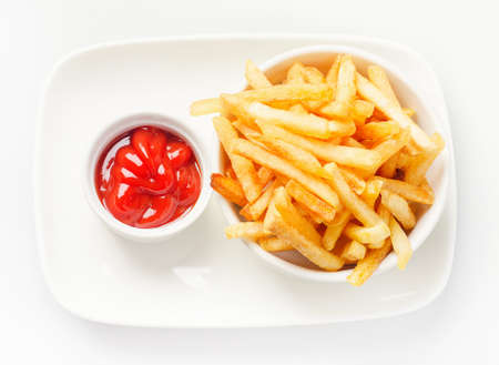 French fries served with tomato sauce on white plate. Top view